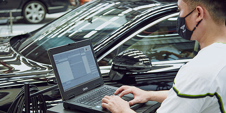 Certified Bentley technician checking on vehicle condition using specialised software.